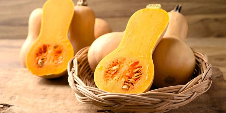 Celá a rozříznutá máslová dýně v košíku