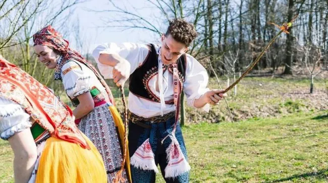 Dva lidé pletem pomlázku tradičním způsobem