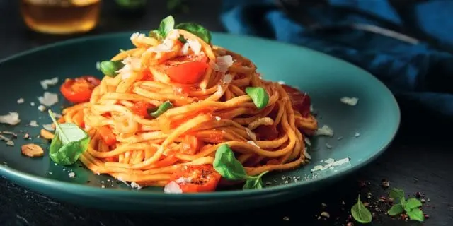Spaghetti s rajčaty a bazalkou na modrém talíři