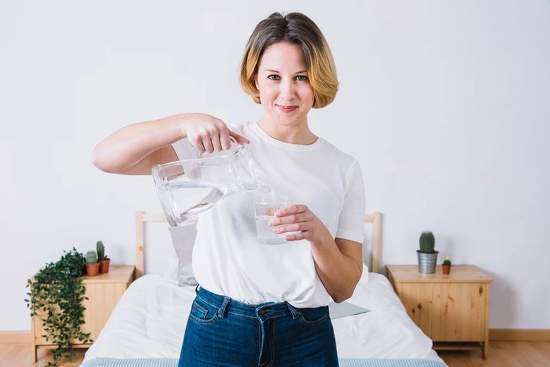 Žena nalévá vodu do sklenice pro vodní půst