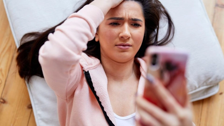 Žena se znepokojeně dívá na telefon