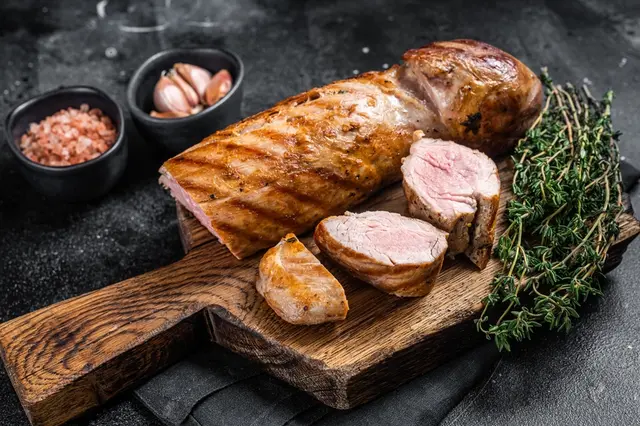 Grilled meat roast na dřevěné desce s bylinkami