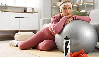 Žena v růžovém sportovním oblečení s fitness vybavením