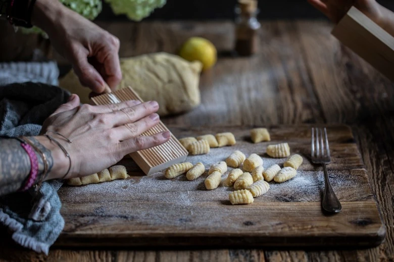 Ruce tvoří gnocchi na dřevěné desce