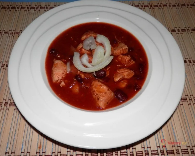 Mexický guláš v bílém talíři s cibulovými kroužky